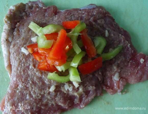 Одну сторону мяса намазать горчицей, положить немного перца и чеснока. Завернуть рулетик, закрепить зубочисткой. Так проделываем со всеми кусками мяса.