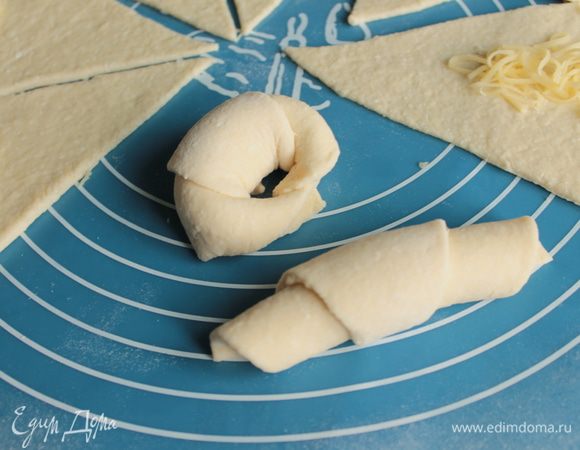  На широкую сторону сегмента кладём сыр. Сворачиваем рулетиком.
Сгибаем подковой и слегка накладываем кончики один на другой, чтобы получился замкнутый «калачик».