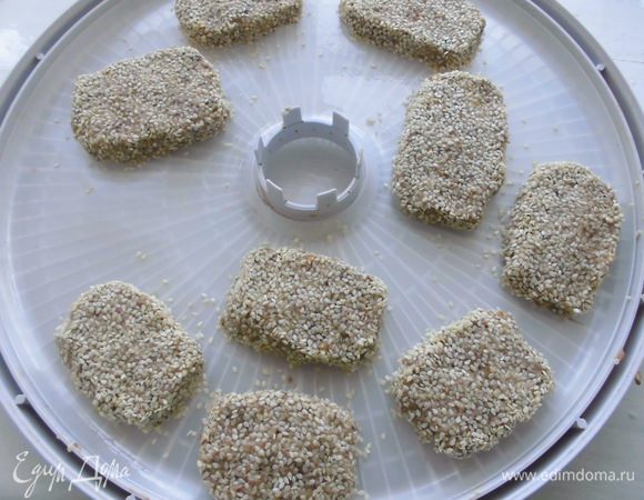Взять небольшое количество "теста", сформировать из него батончик и обвалять в кунжуте. Так поступить со всей массой. Я сразу делала небольшие, но потом стала делать побольше. Честно, все таки лучше делать батончики маленькими- так и на вид красивей, и съесть легче, да и сохнут быстрее. 
Выложить их на лист сушилки (или на противень, выстеленный бумагой для выпечки), сушить при небольшой температуре в дегидраторе или духовке с приоткрытой дверцей. 