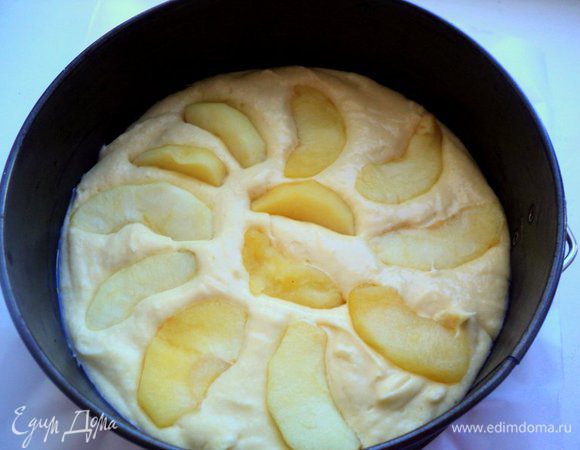 Дно формы Ф-20 см застелить бумагой для выпечки, смазать маслом, вылить тесто. Сверху выложить ¼ часть яблочных долек, вдавив их в тесто.
