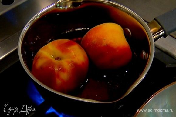 Персики целиком опустить в сироп и немного потомить их, периодически переворачивая.