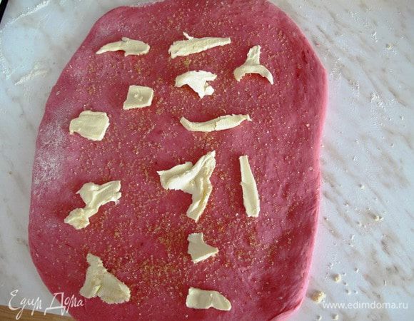 На тесто кладем небольшые кусочки масла и посыпаем сахаром. 