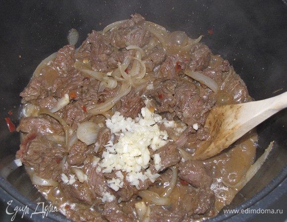 Разогреть в казане или кастрюле с толстым дном 2 ст.л. растительного масла и выложить мясо вместе с маринадом. Помешивая лопаточкой, даем испариться лишней влаге. Как только жидкость немного уменьшилась, добавляем рубленый чеснок, кориандр, хмели-сунели. Перемешиваем. Убавляем огонь до минимума, закрываем крышкой и оставляем томиться 15 минут.