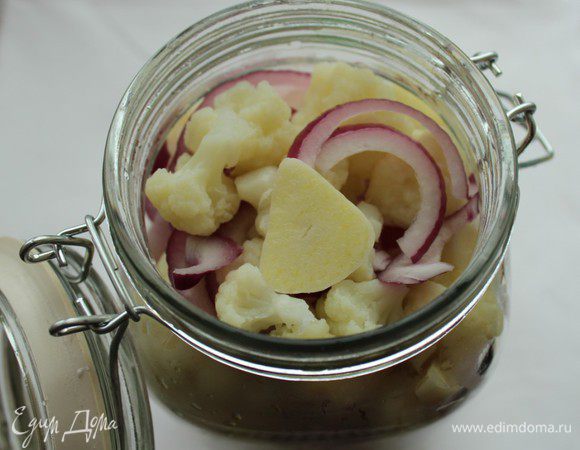 Наполнить банки капустой, луком и чесноком. Залить кипящим маринадом. В каждую банку влить уксус. Такую капусту можно закатать и на зиму. Банки предварительно простерилизовать, а затем стерилизовать наполненные капустой банки в кипящей воде 15 минут. Затем закрыть крышками, перевернуть, укутать и оставить до полного остывания.