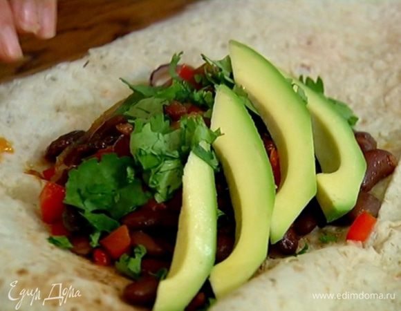 Лаваш разрезать пополам, на каждую половину выложить начинку, посыпать кинзой, сверху поместить полоски авокадо и свернуть рулетами.