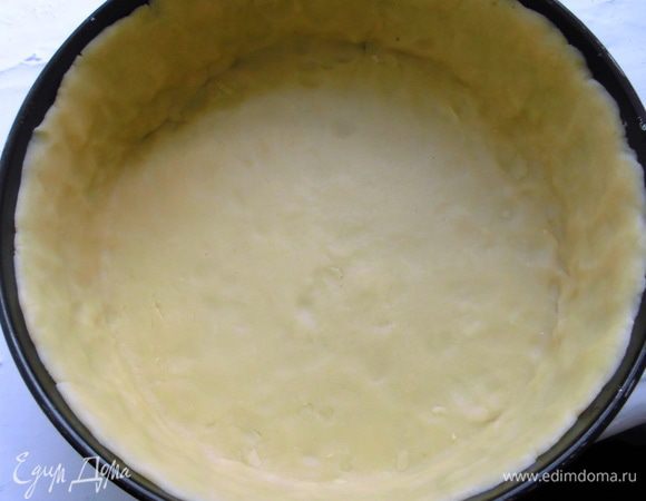 Духовку разогреть до 180 градусов. Тесто вынуть из холодильника, раскатать на присыпанном мукой столе и выложить в форму (у меня 20 см, но можно использовать и 24 см), сделать бортики около 3 см. Наколоть тесто вилкой, накрыть бумагой для выпечки и присыпать горохом или фасолью, можно обыкновенной солью. Выпекать около 20 минут. 