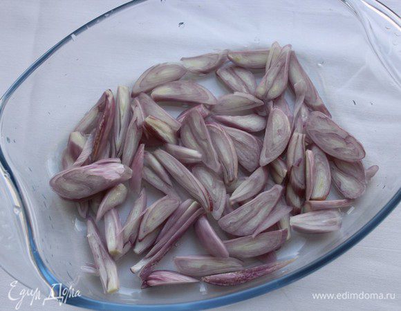 Лук нарезать тонкими полосками или полукольцами, выложить на дно формы для запекания.