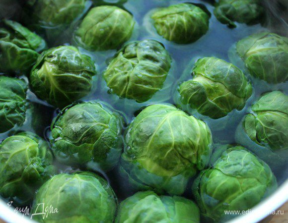 Брюссельскую капусту залить кипятком и варить одну минуту. Это позволит избавиться от горечи. Затем эту воду слить, снова залить кипятком, посолить  и варить 3 минуты при интенсивном кипении. Откинуть на дуршлаг.