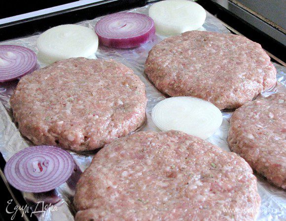 Выложите лук на противень к гамбургерам.