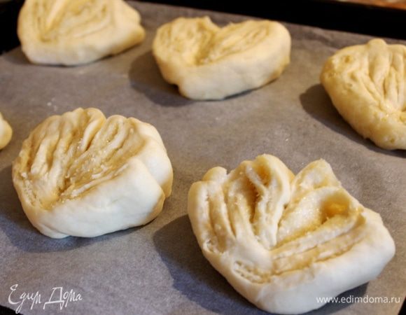 Развернуть половинки срезом вверх, так, чтобы булочки были похожи на веера. В оригинальном малазийском рецепте веера у основания перетягивают листьями пандана, но булочки итак хорошо держат форму. На противень, застеленный пергаментом, выложить булочки. Прикрыть противень полотенцем и оставить для расстойки на 10 минут. 