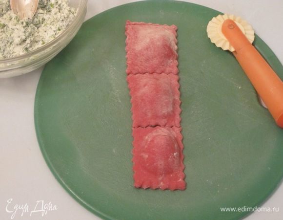 Сложить полоски так, чтобы начинка оказалась внутри. Края защипать. Полоски разрезать на квадраты. Рюмкой прижать середину с начинкой.