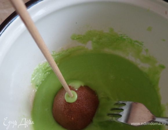 Тем временем приготовить покрытие: 100 г белой глазури растопить на водяной бане и добавить несколько капель красного красителя. Тщательно размешать.
Точно так же сделать порцию зеленой глазури. Если она будет очень густой, можно добавить 1-2 ст.л. воды (что я и сделала).
