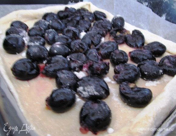 Форму выстилаем пергаментной бумагой. Тесто делим на две части. Раскатываем. Выкладываем одну часть в форму, кладем виноград немного подавленный, чтобы пустил сок (БОльшую половину), равномерно присыпаем сахаром 40 г. 