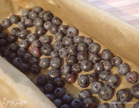 Прямоугольную форму для выпечки выложить пекарской бумагой и праспределить 200 г голубики.