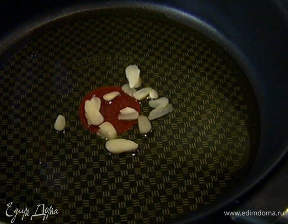 Тяжелый сотейник поместить на огонь, влить 2 ст. ложки оливкового масла и сразу выложить чеснок.