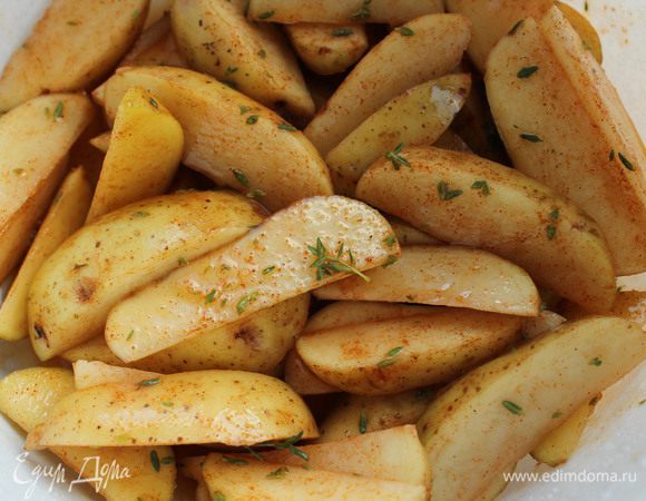 Картофель тщательно помыть, нарезать дольками и залить холодной водой на 15 минут. Воду слить, посыпать рубленым чесноком, листиками тимьяна и перцем,  перемешать, затем полить оливковым маслом и оставить на 5-10 минут.