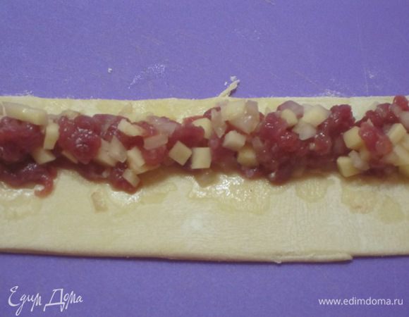 Тесто тонко раскатать, нарезать на полоски шириной 6 см и длиной 22 см. Если так сложится, то хорошо. Но можно изменить размеры полосок. Выложить начинку на полоски ближе к одному краю.