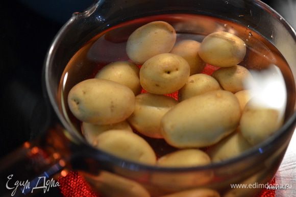 Выложить молодой картофель в кастрюлю, залить водой и поставить на 15-20 мин. Снять с плиты. Дать остыть и разрезать напополам.