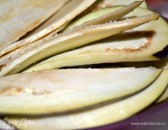 Баклажаны нарезать тонкими пластинами, посыпать солью и оставить на 5 минут. Затем смыть соль и просушить баклажаны на бумажном полотенце.