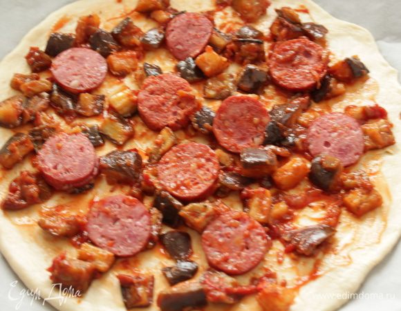 Раскатать тесто, выложить баклажаны, порезанные колбаски.