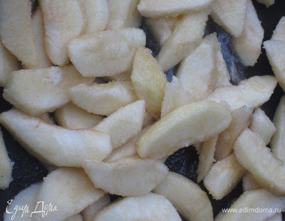 В широкой сковороде разогреть 20 г  сливочного  масла, добавить 60 г сахарa и выложить одну часть яблок. Накрыть крышкой и тушить несколько минут.