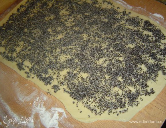 Тесто раскатываем в тонкий пласт,а сверху выкладываем половину маковой начинки и равномерно распределяем по всей поверхности.