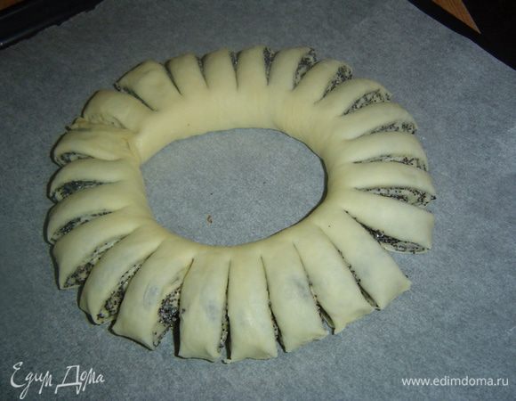 Рулет переносим на пергаментную бумагу, а затем делаем надрезы ножницами, тем самым формируя лепестки. Делаем радиальные надрезы через 1 см, но надрезая не до конца, а оставляя лепестки, скрепленные между собой.