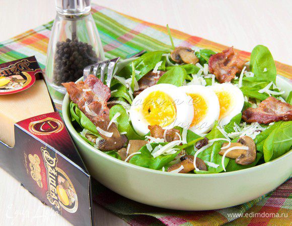 В сковороду, где жарились бекон и грибы, вылить отложенный ранее жир, добавить бальзамический уксус и подержать на огне помешивая 1 минуту. Затем добавить горчицу и ещё немного масла. Как следует перемешать и выключить огонь. Получиться довольно плотный соус с легкой кислинкой. Перебрать шпинат и положить в миску, сверху вылить соус, немного присолить и перемешать шпинат.  Чтобы оформить блюдо порционно распределите шпинат по трем тарелкам.  На каждую тарелку сверху выложить теплые грибы и бекон, присыпать сыром. И украсить все ломтиками яйца. Приятного аппетита!