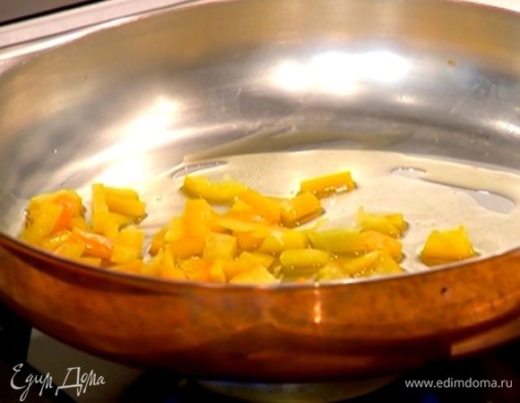 Разогреть в сковороде оливковое масло, выложить сладкий перец, зубчик чеснока, все перемешать и обжаривать 2–3 минуты.