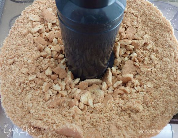 Насыпать в пластиковый пакет немного ванильного печенья и раскрошить  скалкой или перемолоть в комбайне до небольших крошек .