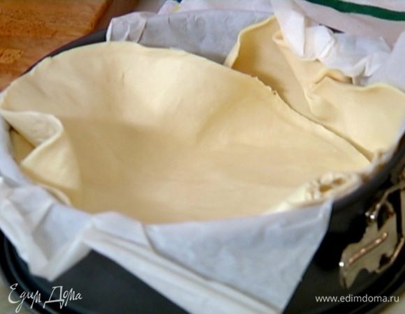 Разъемную форму выстелить бумагой для выпечки, выложить пласт теста так, чтобы получились высокие бортики.