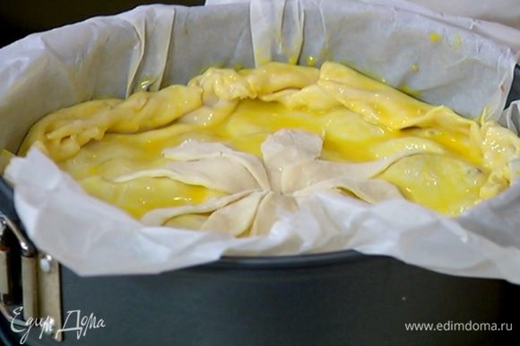 Смазать поверхность пирога желтком, сделать в центре крестообразный надрез, выложить лепестки из теста в форме цветка и тоже промазать его желтком.