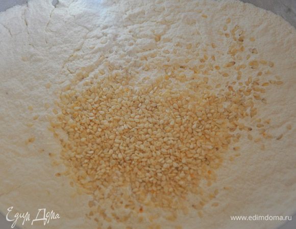 Муку просеять вместе с разрыхлителем, по желанию можно добавить кунжут. 