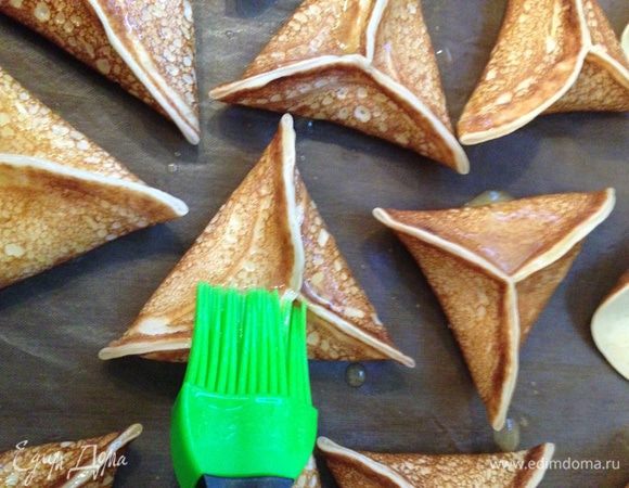 Блины перекладываем на застеленный бумагой для выпечки  противень , смазываем их сверху растопленным сливочным маслом и ставим в разогретую до 180 С духовку на 5–6 минут.