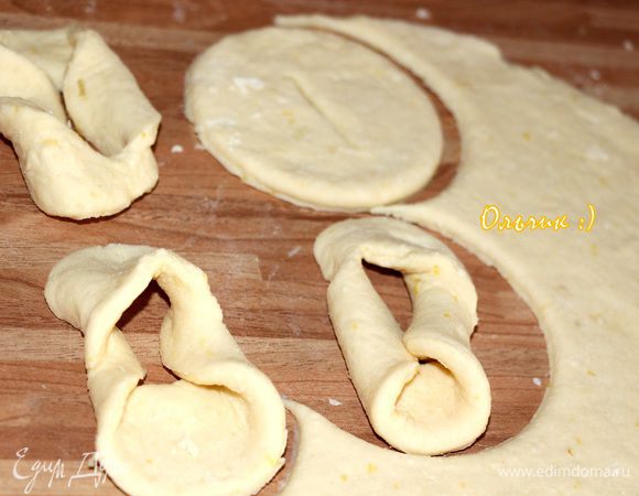 Раскатываем тесто в пласт толщиной 5 мм. Вырезаем стаканом круги, делаем по середине надрез и выворачиваем часть теста сквозь него, по типу хрустиков.