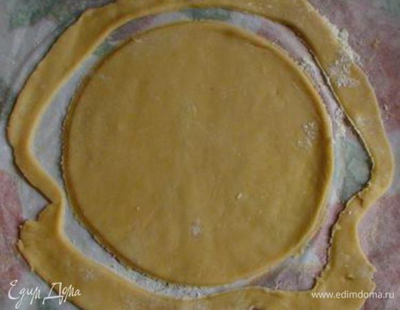 Выложить 1 часть теста на присыпанный мукой пергамент и раскатать (при необходимости можно посыпать мукой). Обрезать корж по дну формы или крышке диаметром 20 см (можно просто надавить крышкой контур круга, а обрезать уже испеченный корж - как удобнее). Обрезки оставить на пергаменте (они понадобятся для оформления боков торта) и все вместе прямо на бумаге перенести на противень.