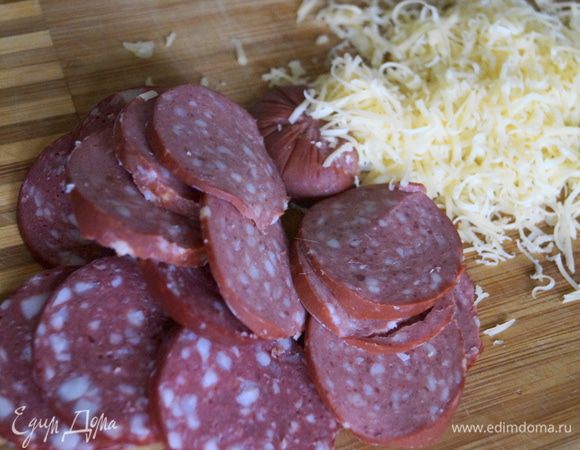 Колбасу нарезать тоненькими кружочками, а сыр Джюгас натереть на мелкой терке