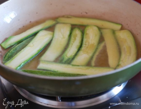 Нарезать цукини тонкими ломтиками. Разогреть на большой сковороде несколько ложек масла с чесноком( только для аромата) и обжарить цукини.