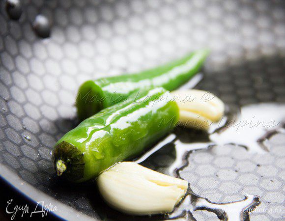 В сковороде разогреть оливковое масло, положить туда перец и чеснок. Обжаривать 3–5 минут, периодически помешивая, затем достать и выбросить. Благодаря этой процедуре у нас получится ароматнейшее острое чесночное масло для креветок.