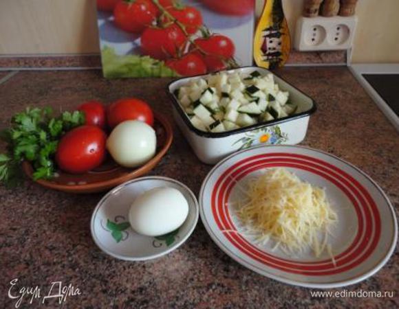 Яйцо залить холодной водой и поставить варить на 10 минут. Духовку включить для разогрева до 220-250 градусов.
Кабачки очистить (если кабачки молодые с нежной кожицей, то чистить не надо), нарезать на кубики. Лук мелко порубить. Помидоры нарезать кубиками.
