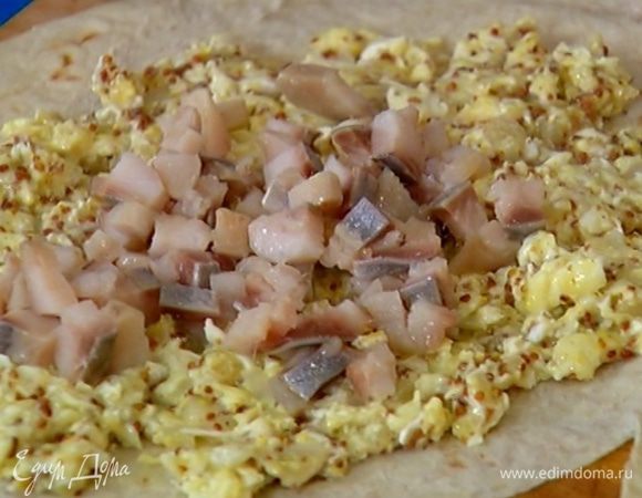 Лаваш разрезать пополам, на одну половину равномерно выложить начинку из яиц, сверху разложить сельдь.