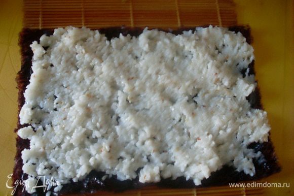 Распределить рис по листочку нори, стараясь выкладывать не слишком толстым слоем.