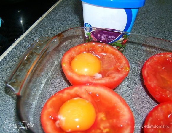 В каждую помидору разбить сырое яйцо. Положить по небольшому кусочку сливочного масла.