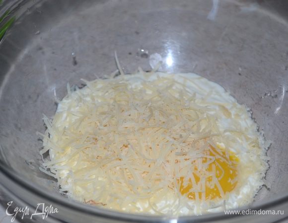 В миске смешиваем куриные желтки, натертый сыр, сметану, лимонный сок и рубленую зелень петрушки.