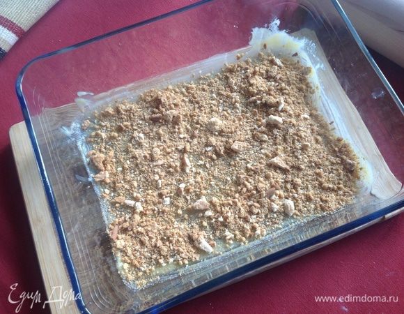 Смазать форму, обильно, сливочным маслом и присыпать половиной раскрошенного печенья.
