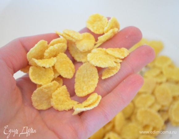 В большой миске смешать сахар, орехи и хлопья.