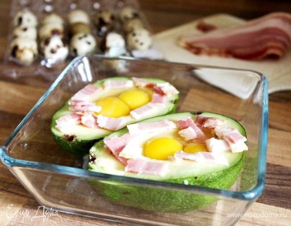 Авокадо разрезать пополам и удалить кость. В углубление от косточки уложить кусочки бекона и влить яйцо.