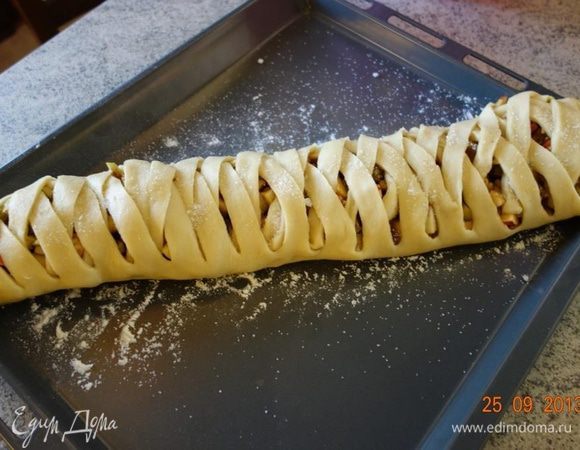 Заплести боковые полоски из стороны в сторону. Плетенку переложить на посыпанный мукой противень и сверху обсыпать оставшихся сахаром (20 г).