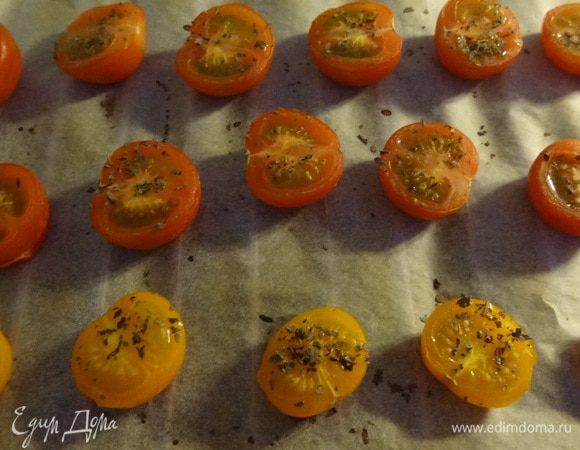Помидоры черри помыть и разрезать вдоль. Затем уложить на застеленный бумагой для выпекания противень, присыпать сушеным базиликом и запечь в духовке до состояния "легкого сморщивания". 