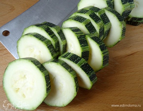 Включить духовку на 220 гр. 
В кастрюльку налить 1,5 ст. воды, поставить на огонь. Рис промыть и всыпать в воду. Посолить. Как вода закипит, рис помешать. Варить до готовности.
Пока варится рис. Форму смазать маслом. Кабачок, нарезать на кольца по 0,7-1 см толщиной.